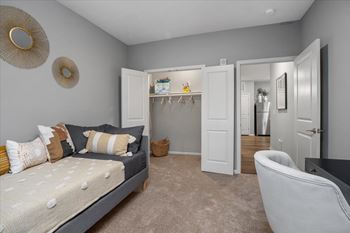 A bedroom with a bed, chair, and wardrobe.